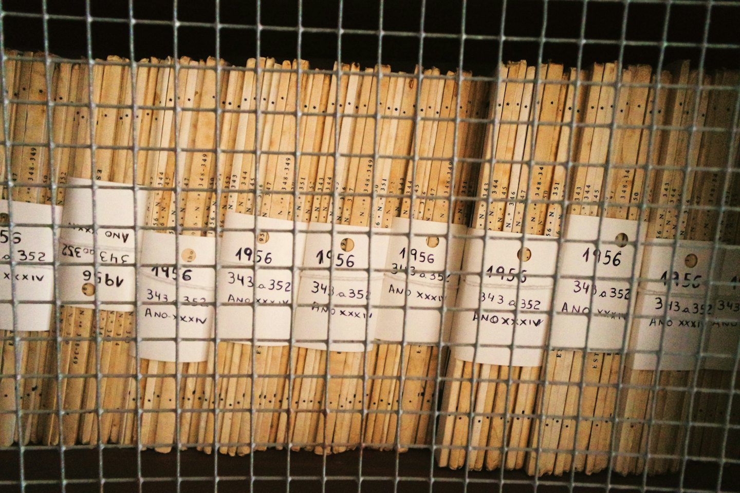 Old archival documents stored vertically in a metal rack.
